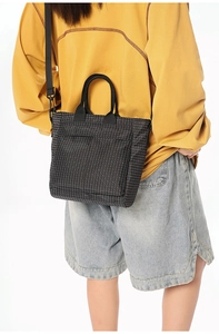 Detail of black grid tote bag with adjustable shoulder strap and large front pocket