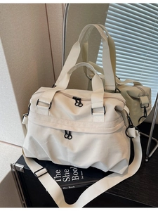 Minimalist large capacity cream canvas tote bag with adjustable strap on black wood