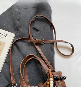 Détail du sac seau tressé avec bandoulière réglable et breloque en perles colorées