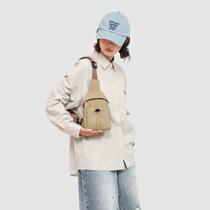 Detail view of the khaki crossbody bag with drawstring pocket and adjustable brown strap