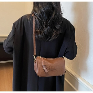 Vue détaillée de la texture en cuir litchi marron sur un sac bandoulière élégant