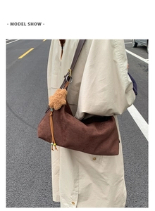 Detailed view of brown frosted hobo bag with teddy charm and beaded tassel on trench coat