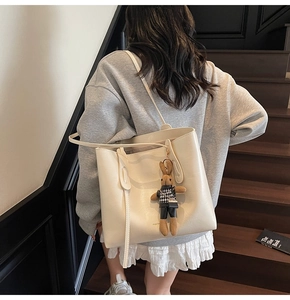 Detail of cream white leather tote bag with a houndstooth bunny charm on a model