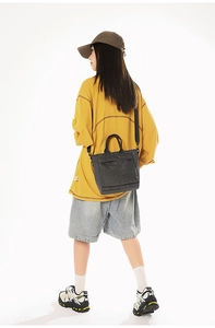 Detail of the grey checkered tote bag with black webbing handles and nylon shoulder strap