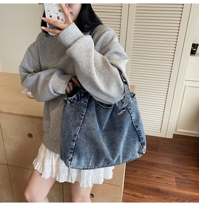 Lifestyle shot of large washed blue denim tote bag worn on shoulder in a home setting