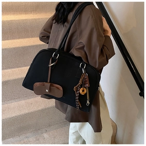 Dettaglio borsa a spalla nera opaca con pochette marrone e charms a forma di ciambella