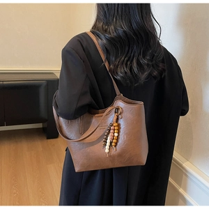 Detail of dark brown leather tote bag with unique wood and ceramic bead tassel accessory