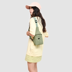 Detail of grass green outdoor chest bag featuring elastic drawstrings and adjustable strap