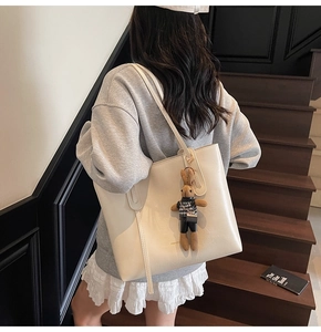 Detail of a large cream tote bag featuring a cute brown bunny charm and houndstooth vest