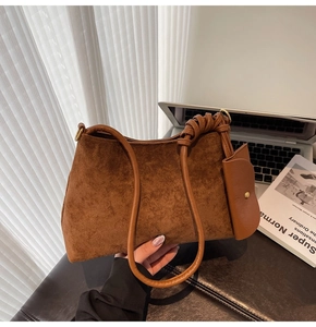 Detail of a brown suede shoulder bag featuring a unique decorative knotted strap design
