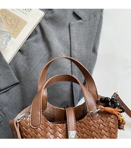 Détail du sac seau marron tressé avec breloque en perles et poignées en cuir