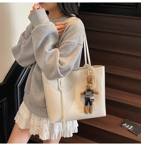 Detail of cream leather tote bag with fashion text and houndstooth bunny charm accessory
