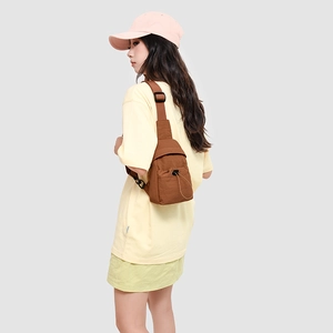 Detail of brown crossbody bag featuring drawstring zipper pocket and adjustable strap