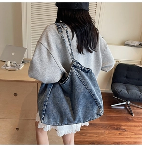 Detail of vintage denim hobo bag with metal chain strap and white ruffle trim detail