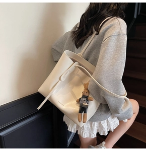 Detail of off-white leather tote bag with long straps and a cute brown rabbit charm