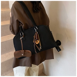 Dettaglio della grande borsa a tracolla nera con eleganti ciondoli in pelle marrone e accessori