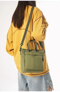 Detail of the olive green nylon crossbody bag showing dual handles and adjustable strap