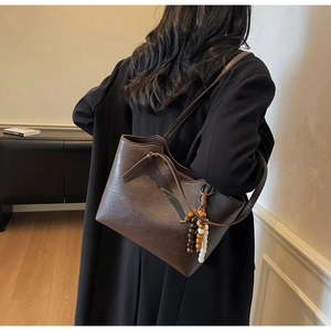 Detail of dark brown PU leather tote bag with stylish beaded tassel and printed logo