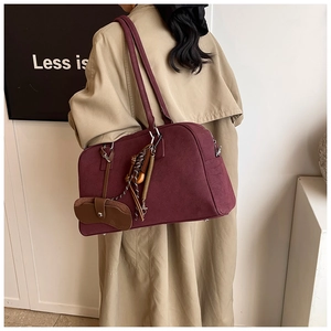 Borsa tote in camoscio bordeaux con ciondolo indossata su trench color kaki