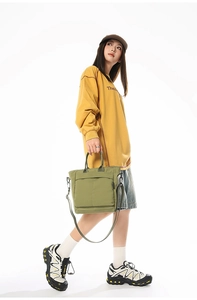 Detail view of olive green canvas tote bag showing the zipper pocket and detachable strap