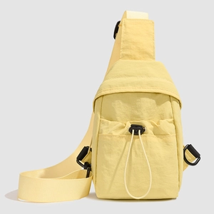 Front detail of pale yellow nylon crossbody bag featuring a drawstring front pocket