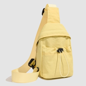 Detail of light yellow nylon crossbody bag with drawstring pocket and adjustable strap