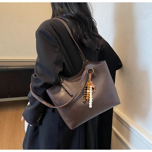 Detail of dark brown vintage leather shoulder bag with wooden bead tassel on a model