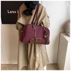 Dettaglio della borsa tote bordeaux opaca con manici in pelle e ciondoli vintage curati