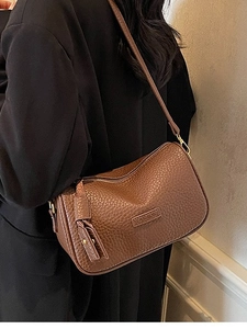 Sac oreiller en cuir marron texturé avec large bandoulière vue de profil sur mannequin