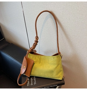 Close-up of green faux suede shoulder bag with brown strap and small coin pouch