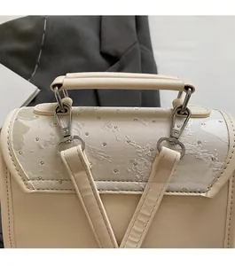Detail of elegant gold metal hook and shimmering ripple texture on a beige fashion backpack