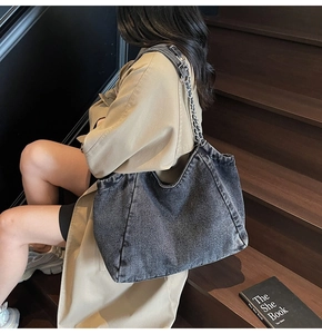 Detail of grey washed denim tote bag with metal chain strap and casual textured fabric