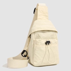 Detail of cream nylon crossbody bag with black drawstring pocket and adjustable strap