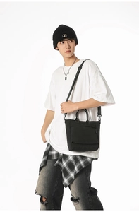 Detailed view of black nylon tote bag showing adjustable straps and front pocket