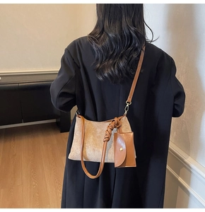 Detail of suede shoulder bag with knot strap and matching leather pouch insert