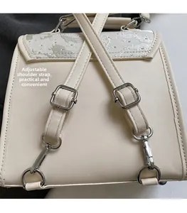 Detail of beige backpack featuring adjustable shoulder straps and silver metal hardware