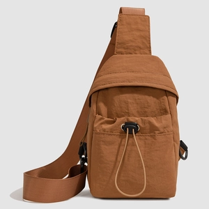 Detail of caramel brown ripstop nylon crossbody bag showing the adjustable drawstring front pocket