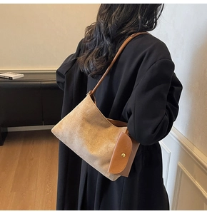 Detail view of camel suede shoulder bag showing side flap pocket and leather strap