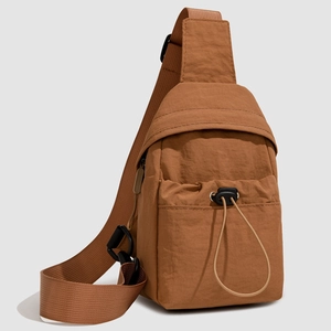 Detailed view of brown crossbody bag featuring front drawstring pocket and wide nylon strap