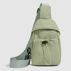 Detail of light green nylon crossbody bag showing the adjustable drawstring front pocket