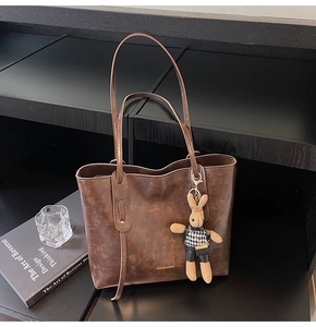 Detail of dark brown vintage tote bag featuring a bunny charm and textured finish