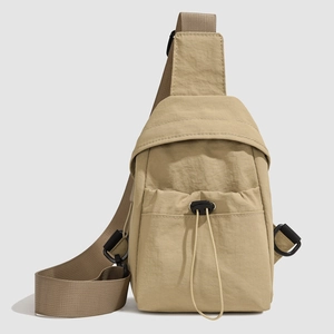 Detail of khaki nylon crossbody bag showing drawstring pocket and wide adjustable strap