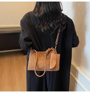 Detail of a brown suede tote bag featuring a knotted shoulder strap and matching mini pouch