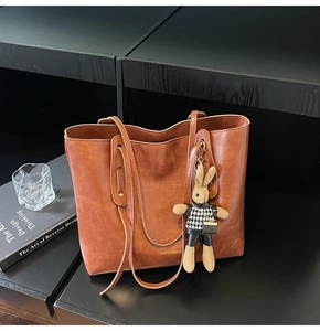 Close-up of vintage brown tote bag with fashion lettering and cute rabbit charm detail