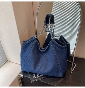 Detailed view of dark blue denim tote bag with silver chain strap and large capacity