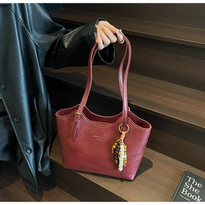 Detail of burgundy leather tote bag with vintage texture and colorful bead tassel