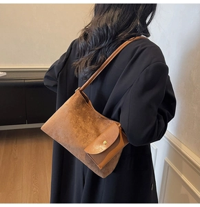 Detailed texture of brown suede shoulder bag with small attached flap coin purse accessory