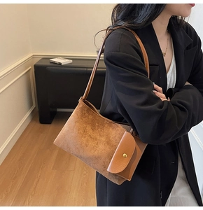 Detail of vintage brown suede shoulder bag with gold buckle on a black blazer
