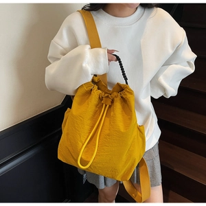 Dettaglio di uno zaino in nylon giallo zenzero con coulisse, mostrato da una modella