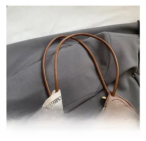 Detail showing the brown woven leather texture and a decorative lettered webbing strap